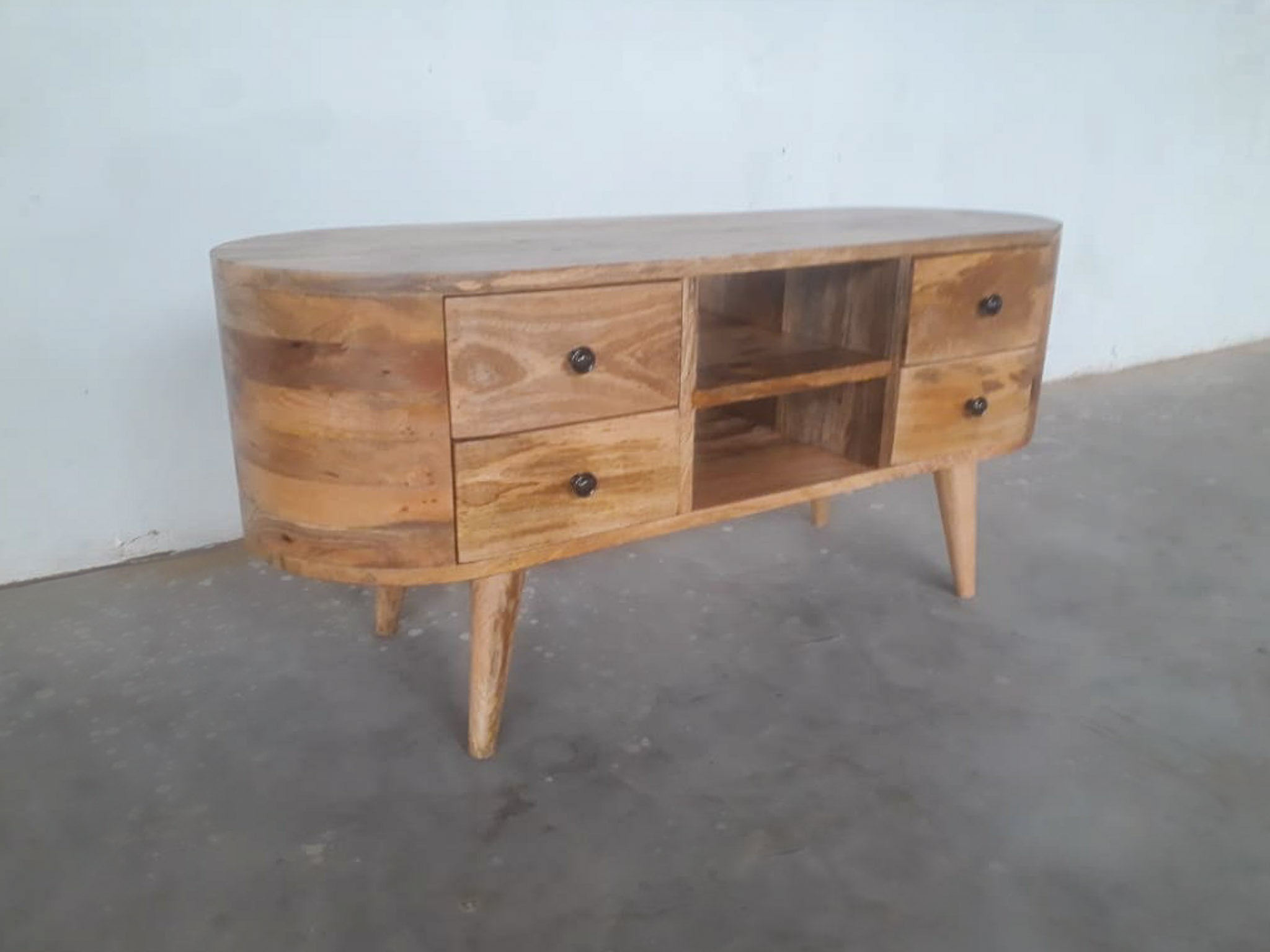 Wooden sideboard with drawers and shelves on a concrete floor.