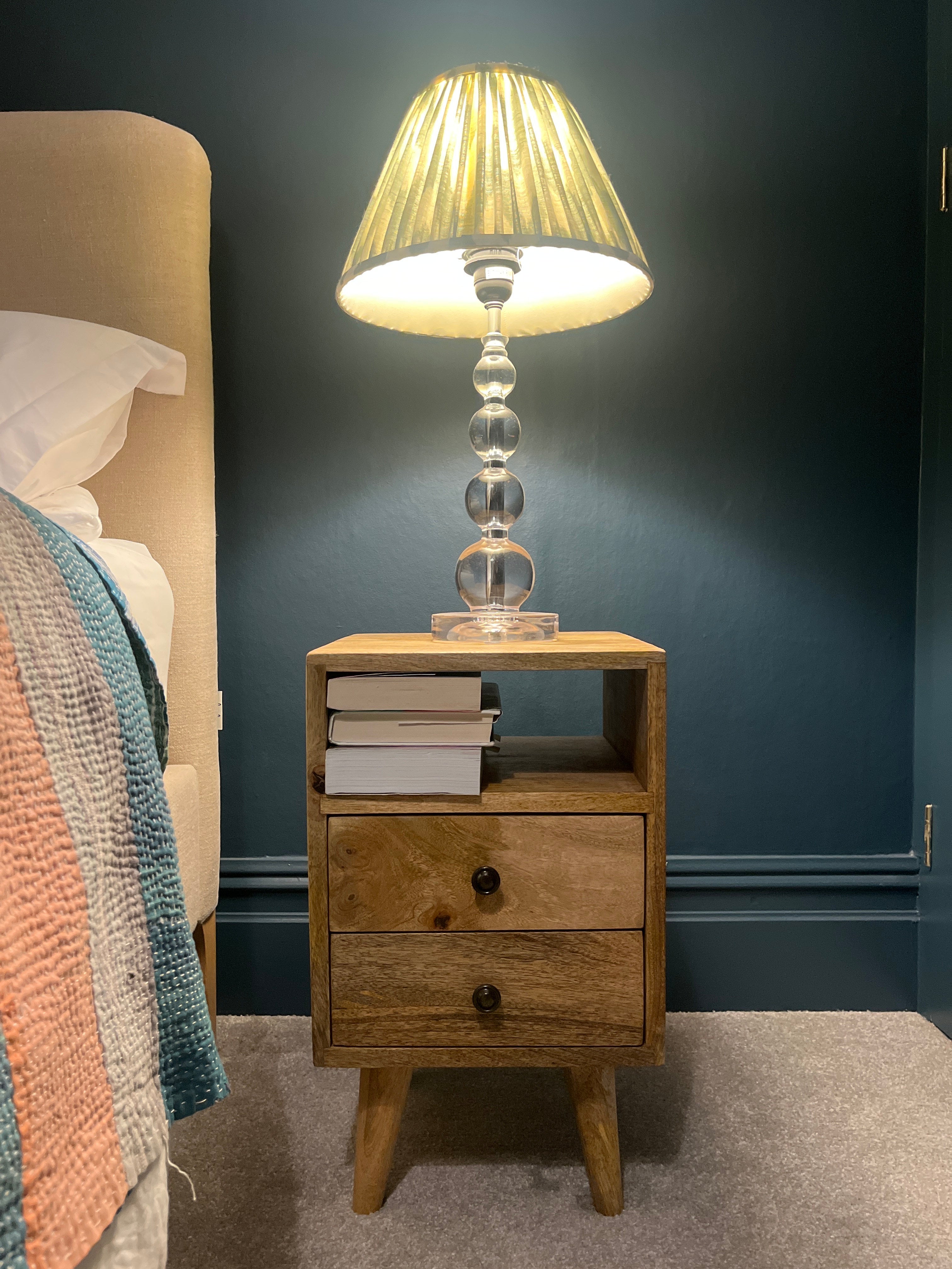 A stylish navy bedroom featuring a wooden bedside in a light brown finish.