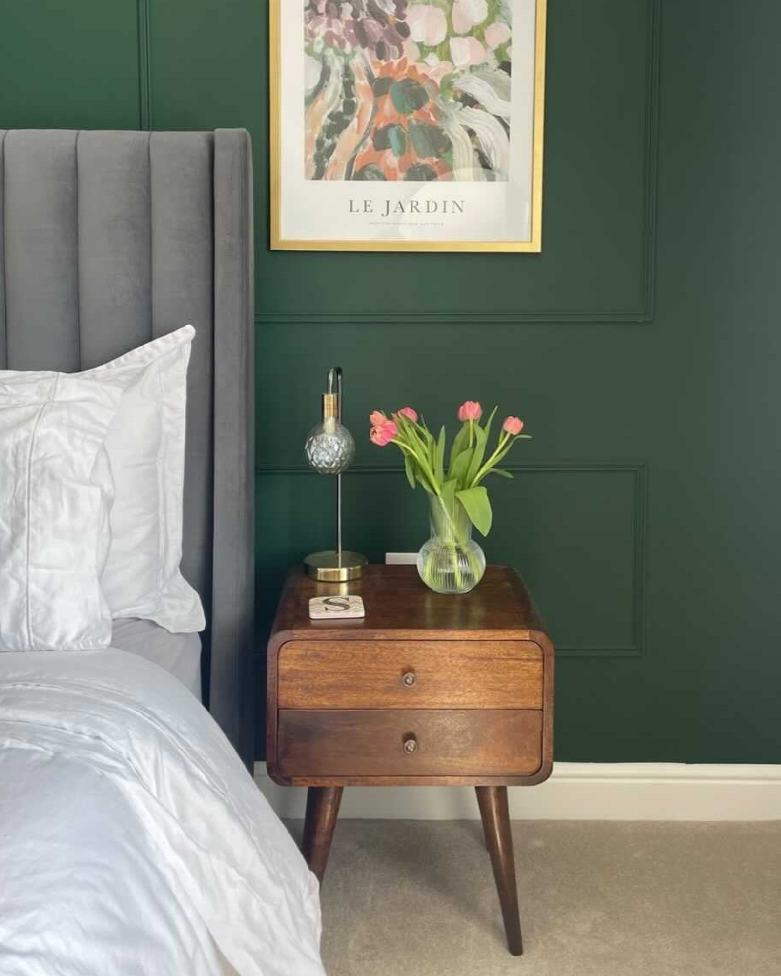 A stylish green bedroom featuring a curved nightstand in a dark brown mango wood stain.