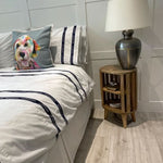 Bedroom with a bed featuring decorative pillows and a wooden side table with a lamp.