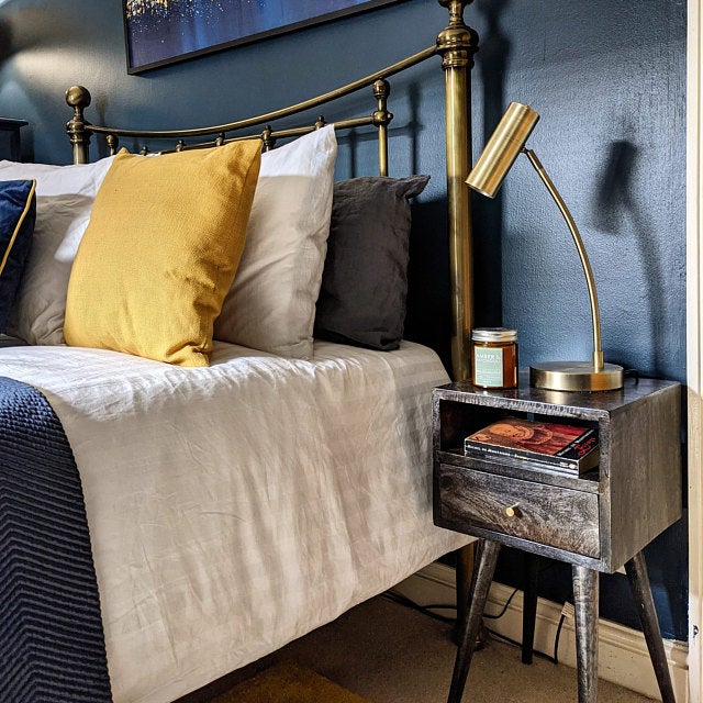 Stylish bedroom featuring a small, black wooden bedside table.