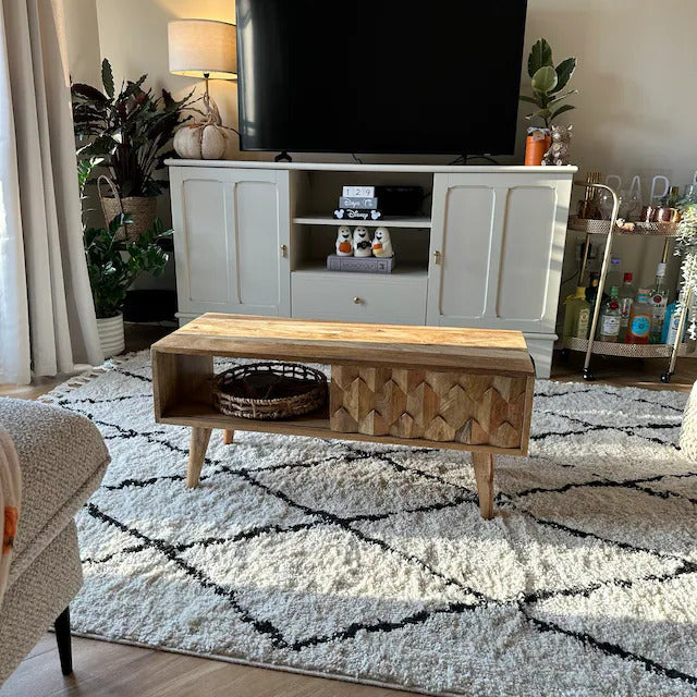 A neutral living room featuring a textured carved coffee table in a light brown wood finish.