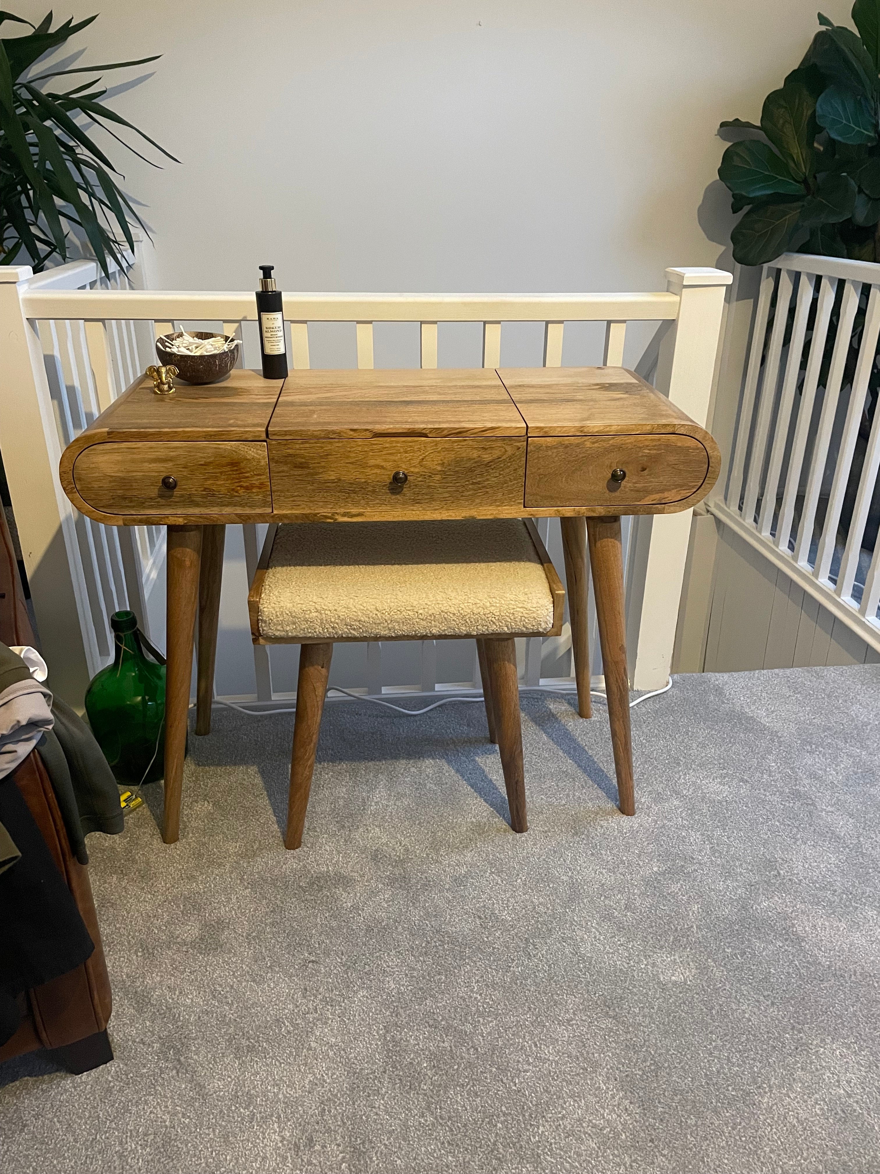 Curved dressing table in a light brown stain, with a square boucle bench.