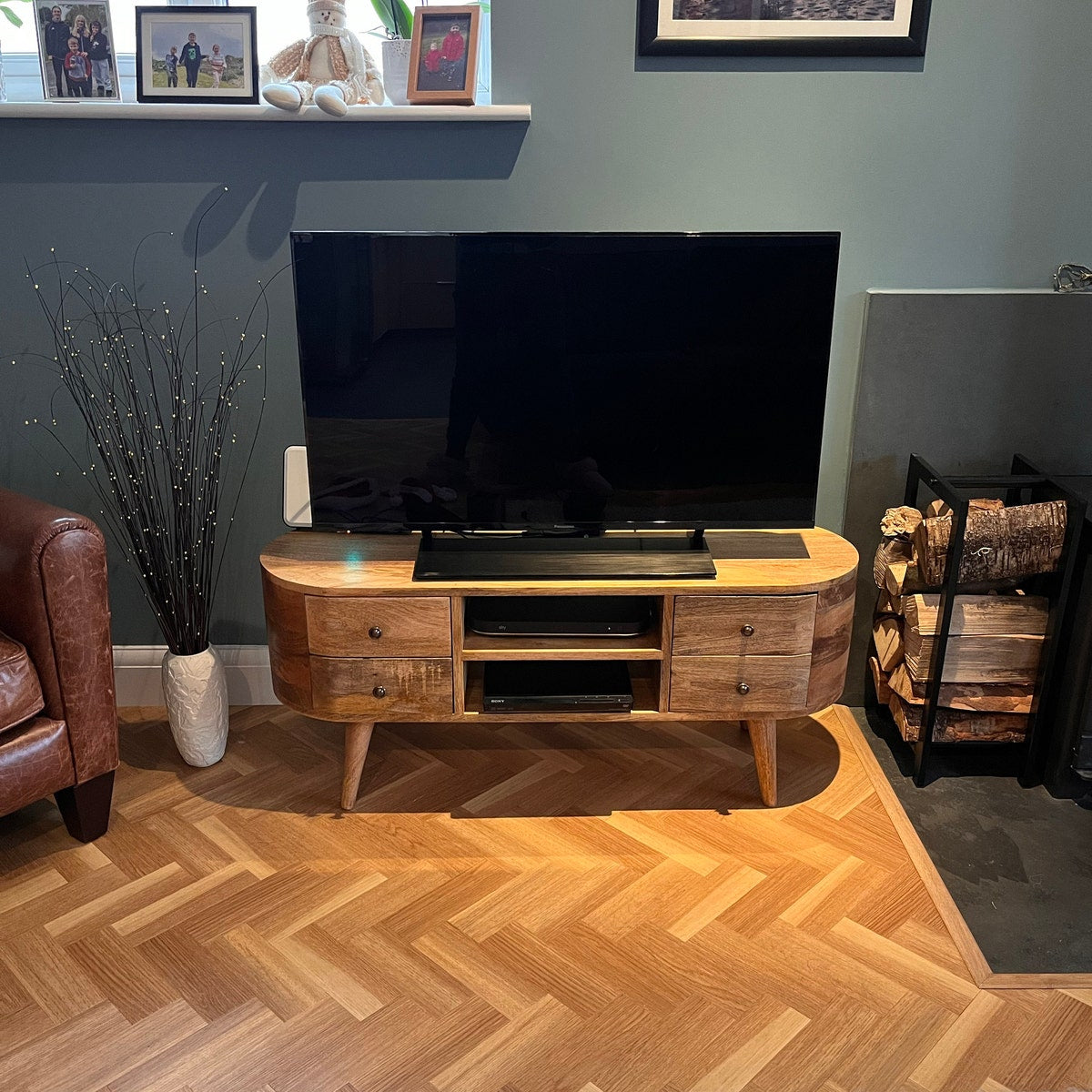 A large round TV stand made from mango wood, styled in a living room.