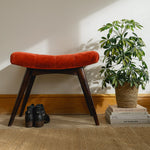 Curved bench upholstered in red fabric, with a dark mango wood body and legs.