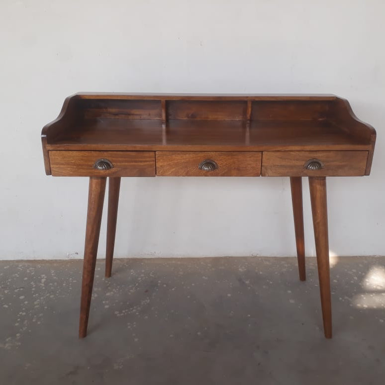 Bespoke mango wood desk in chestnut,  with three drawers against a plain wall.