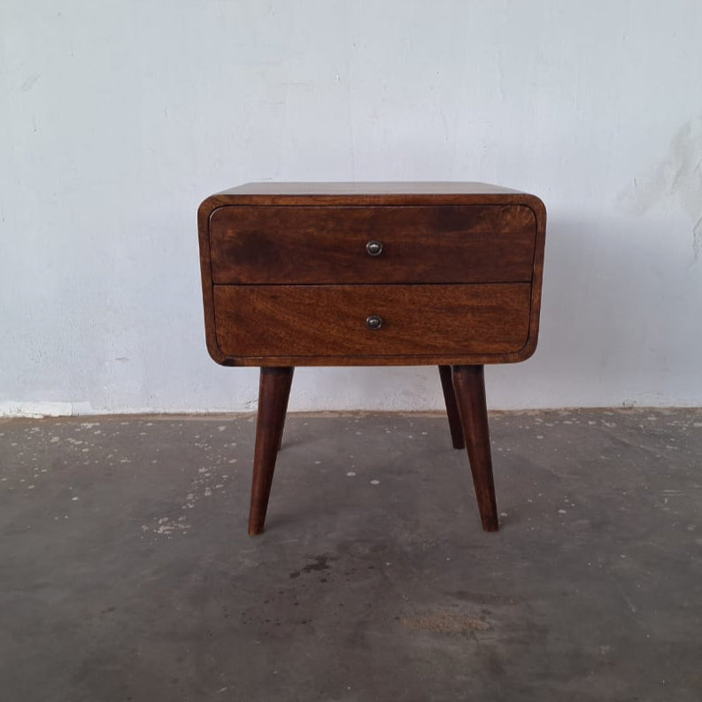 Wooden bedside table with two drawers on a gray floor against a white wall