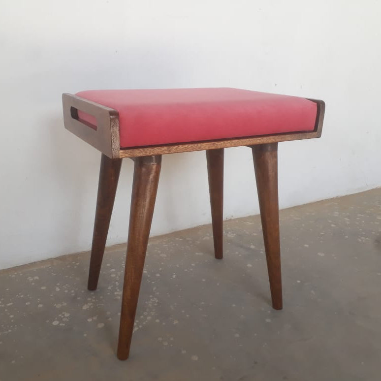 Wooden stool with a red cushion on a plain floor and wall background
