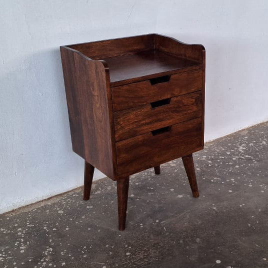 Mango wood bedside table against a white wall on a concrete floor