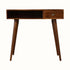 Nordic-style desk in a dark brown wooden finish, with an open slot shelf, single storage drawer, brass hardware and tapered legs.