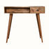 Desk crafted from solid mango wood in a light brown natural finish, with brass shell handle, one storage drawer and an open slot shelf. 