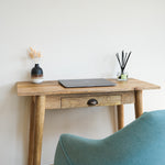A compact writing desk with a laptop and decorative objects on top, Nordic style.