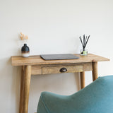 A compact writing desk with a laptop and decorative objects on top, Nordic style.