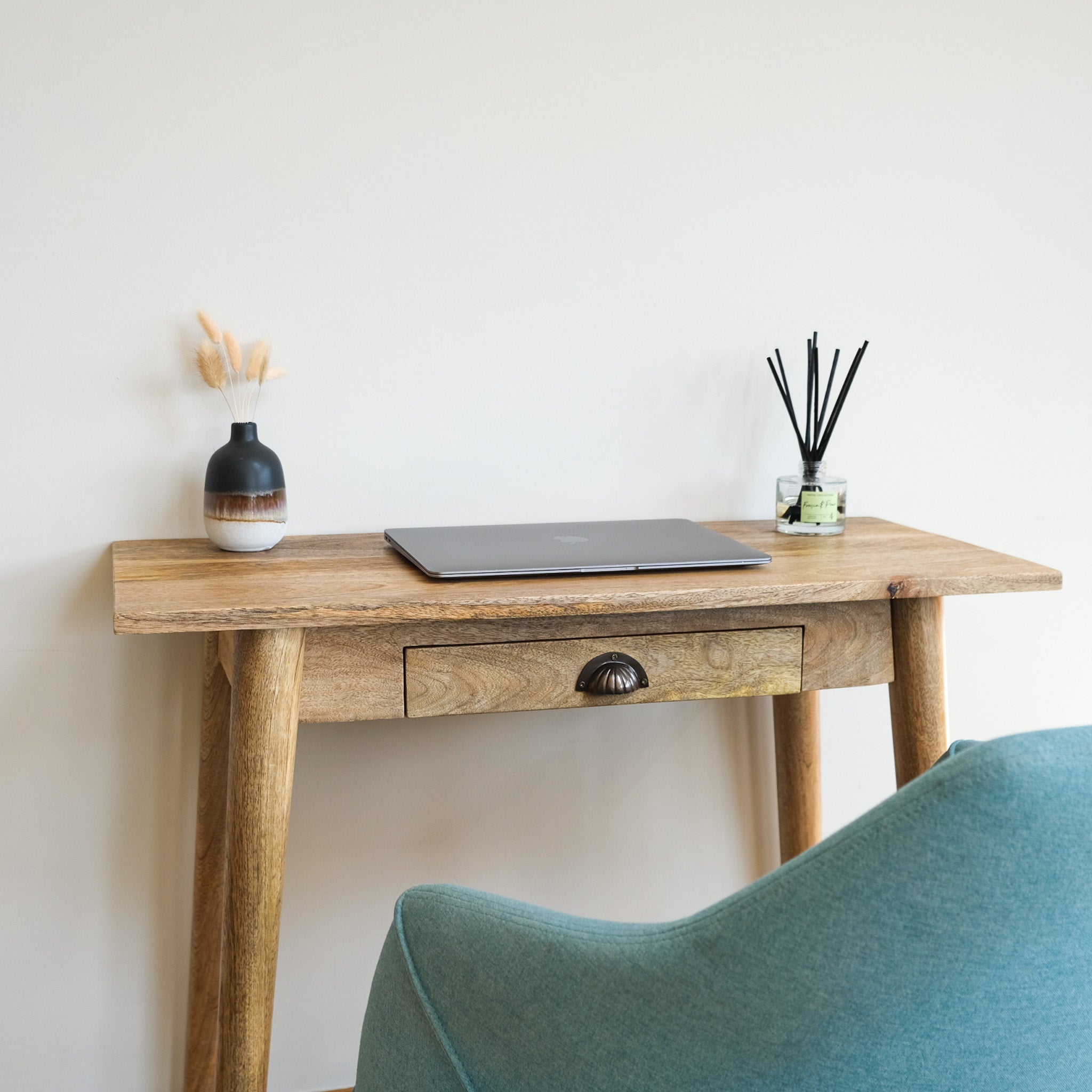 A compact writing desk with a laptop and decorative objects on top, Nordic style.
