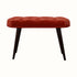 Curved stool with deep button top, upholstered in red fabric and dark wood legs. 