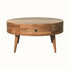 Oval shaped coffee table with storage drawers, short tapered legs, crafted from mango wood in a natural brown finish.