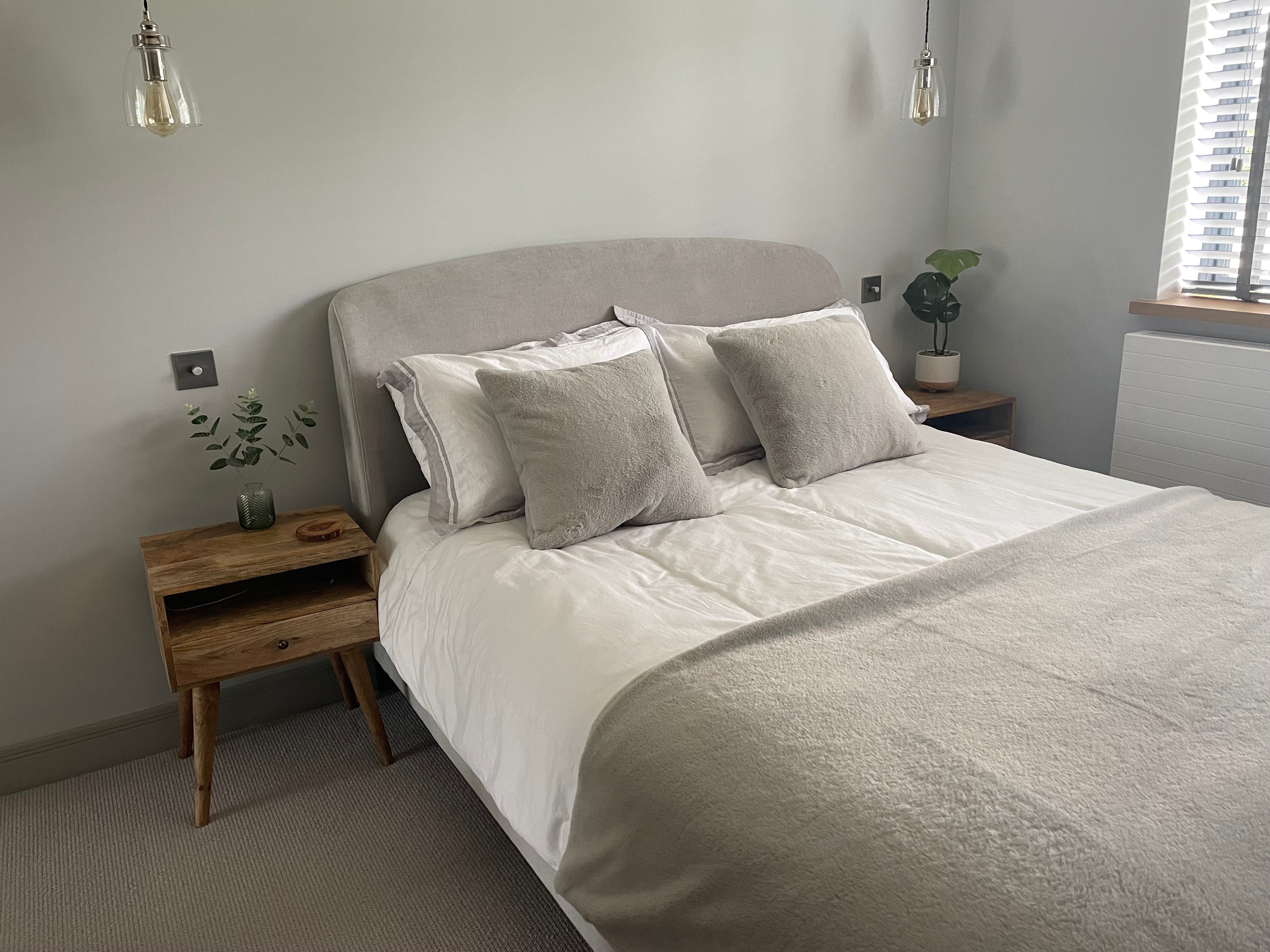 Neatly made bed with gray bedding in a bedroom setting.