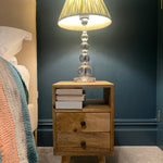 A stylish navy bedroom featuring a wooden bedside in a light brown finish.