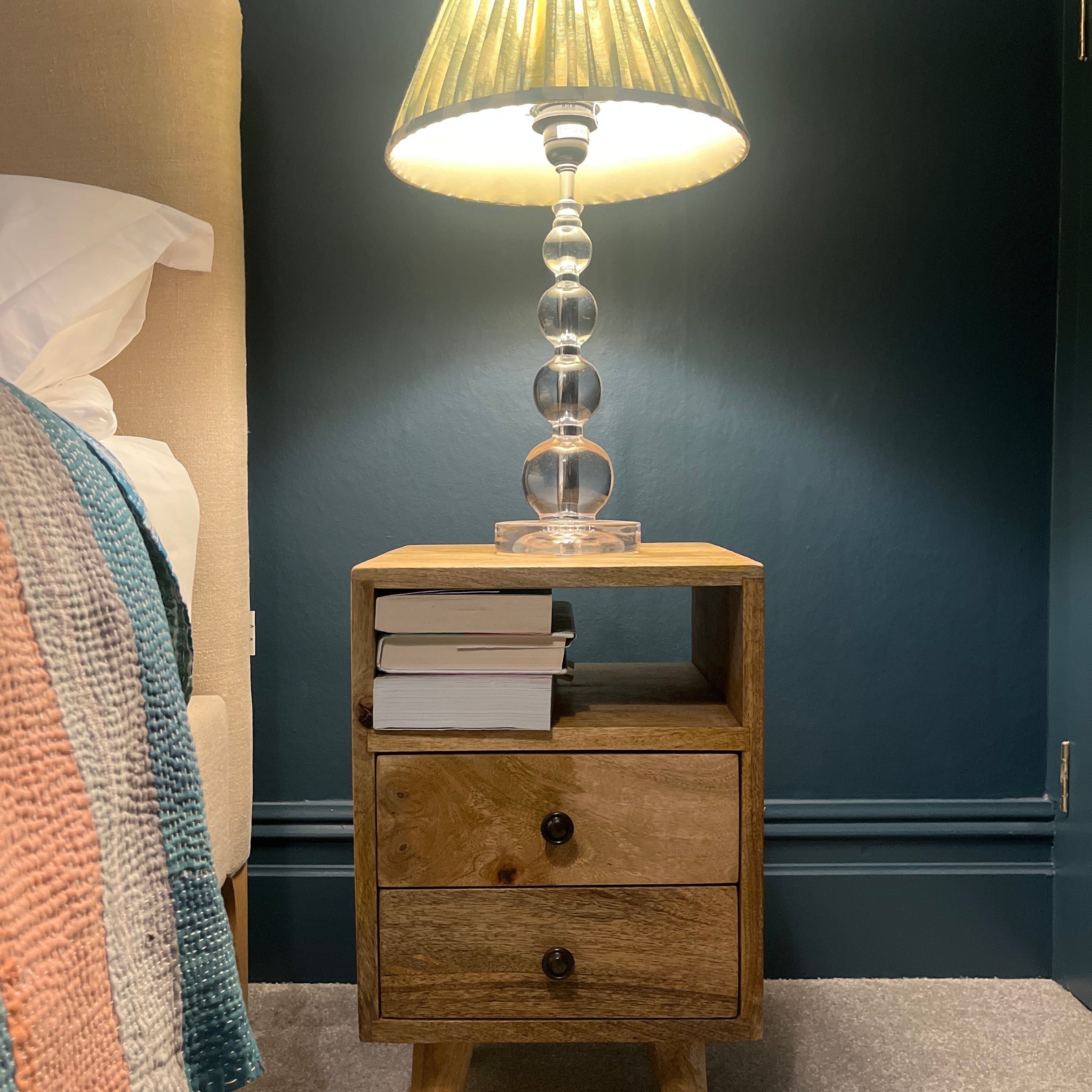 A stylish navy bedroom featuring a wooden bedside in a light brown finish.