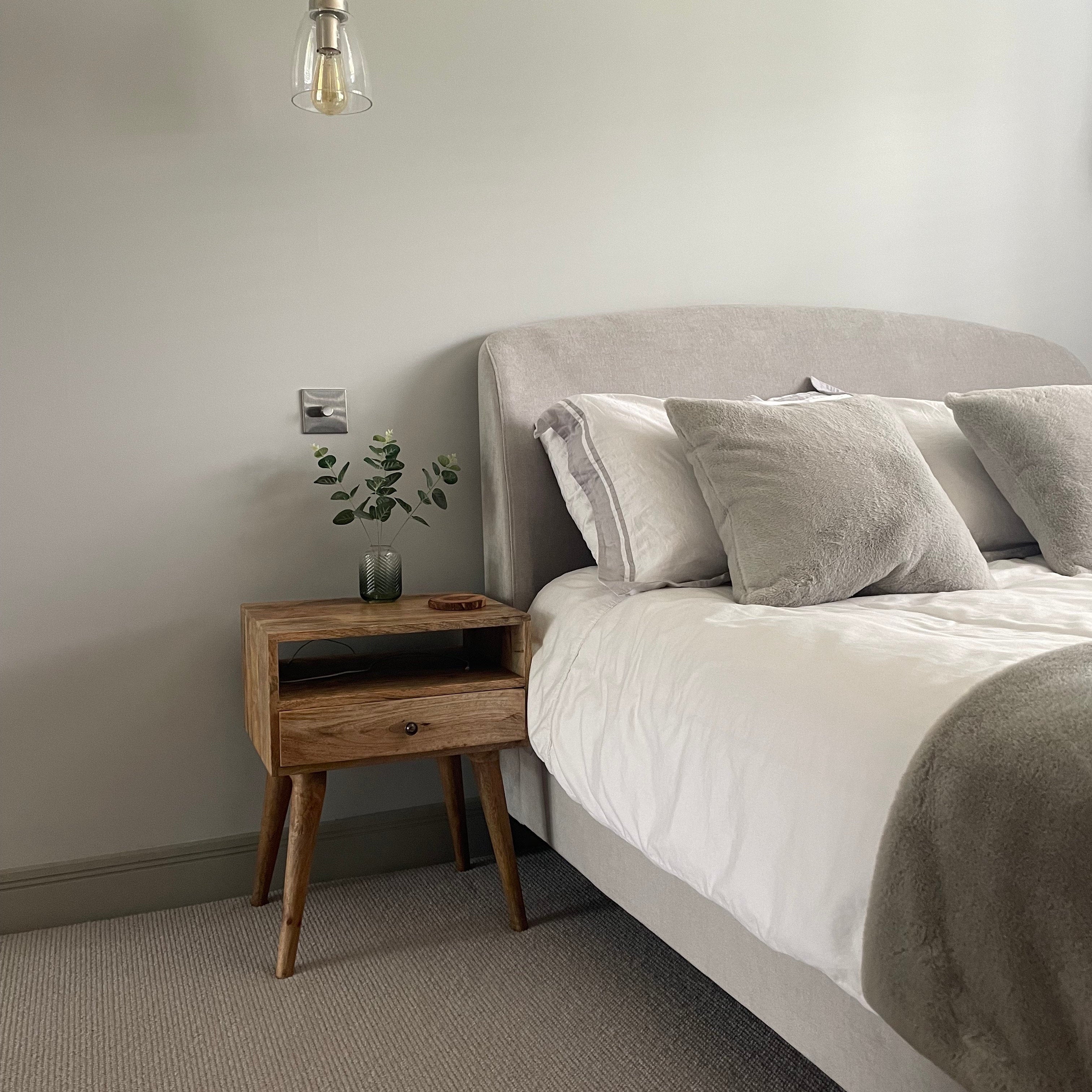 A stylish and neutral bedroom setup, featuring a square shaped bedside table, made from mango wood in a light brown finish.