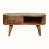 A small round coffee table made of natural wood with brass knob detailing, featuring an open slot shelf and a single drawer.