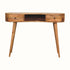 A large, natural finish mango wood writing desk with an open slot shelf and two drawers, featuring a brass knob and four tapered legs.