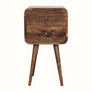 A small bedside table with four legs, made of mango wood with a grey wash finish, featuring two drawers with brass knobs.