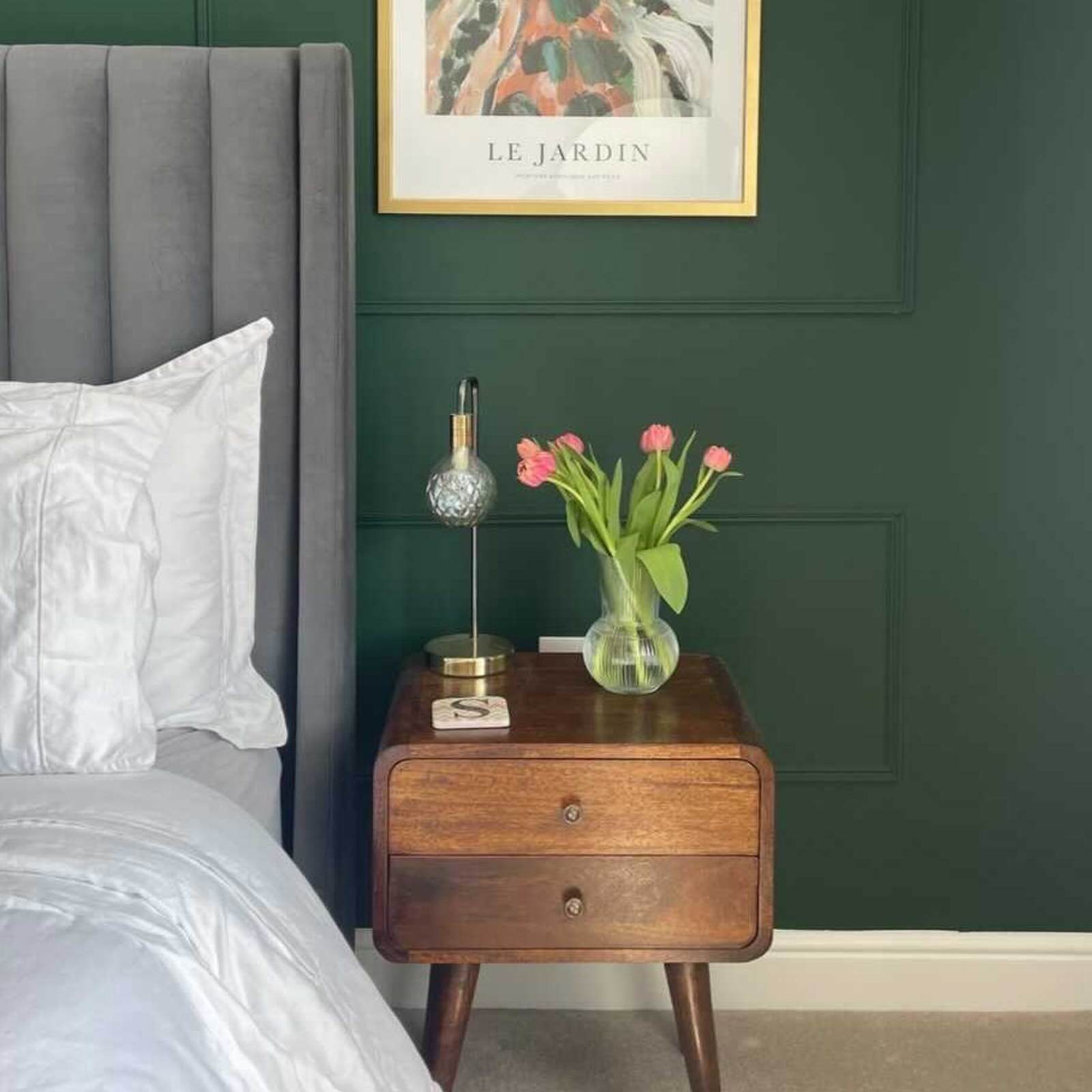 A stylish green bedroom featuring a curved nightstand in a dark brown mango wood stain.