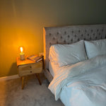 Bedroom with a tufted headboard, nightstand with lamp, and books.