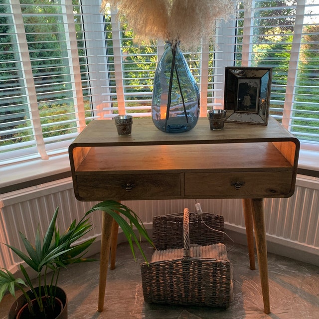 Wooden console table with decorative items in a room with large windows.