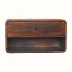 A wall-mounted bedside table made of mango wood in a chestnut finish, featuring an open slot shelf and a drawer with a brass knob.