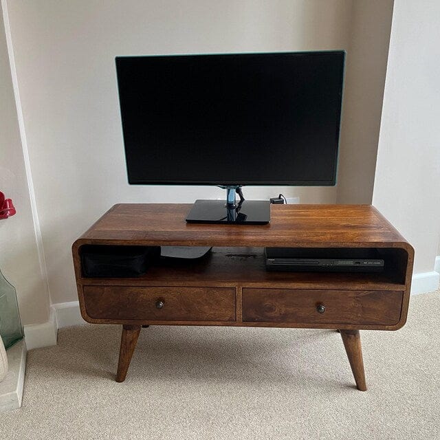 Wooden TV stand with a television on top in a room setting.