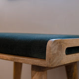 Close up shot of bench made from solid light brow wood, with a green velvet seating pad.