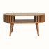 A medium-sized round coffee table made of natural finish mango wood, featuring a slatted design and an open shelf.