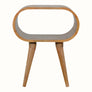 A natural finish mango wood bedside table with an open slot shelf and a sturdy leg, designed for storage and display.