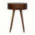 A chestnut finish bedside table with a round top and a single drawer, featuring brass knob handles on the drawer and four wooden legs.