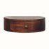 Floating circular bedside table made from solid wood in dark brown stain.