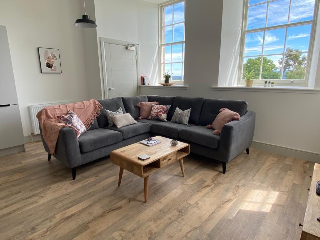 lIving room with a gray L-shape sofa, wooden coffee table, and large windows.