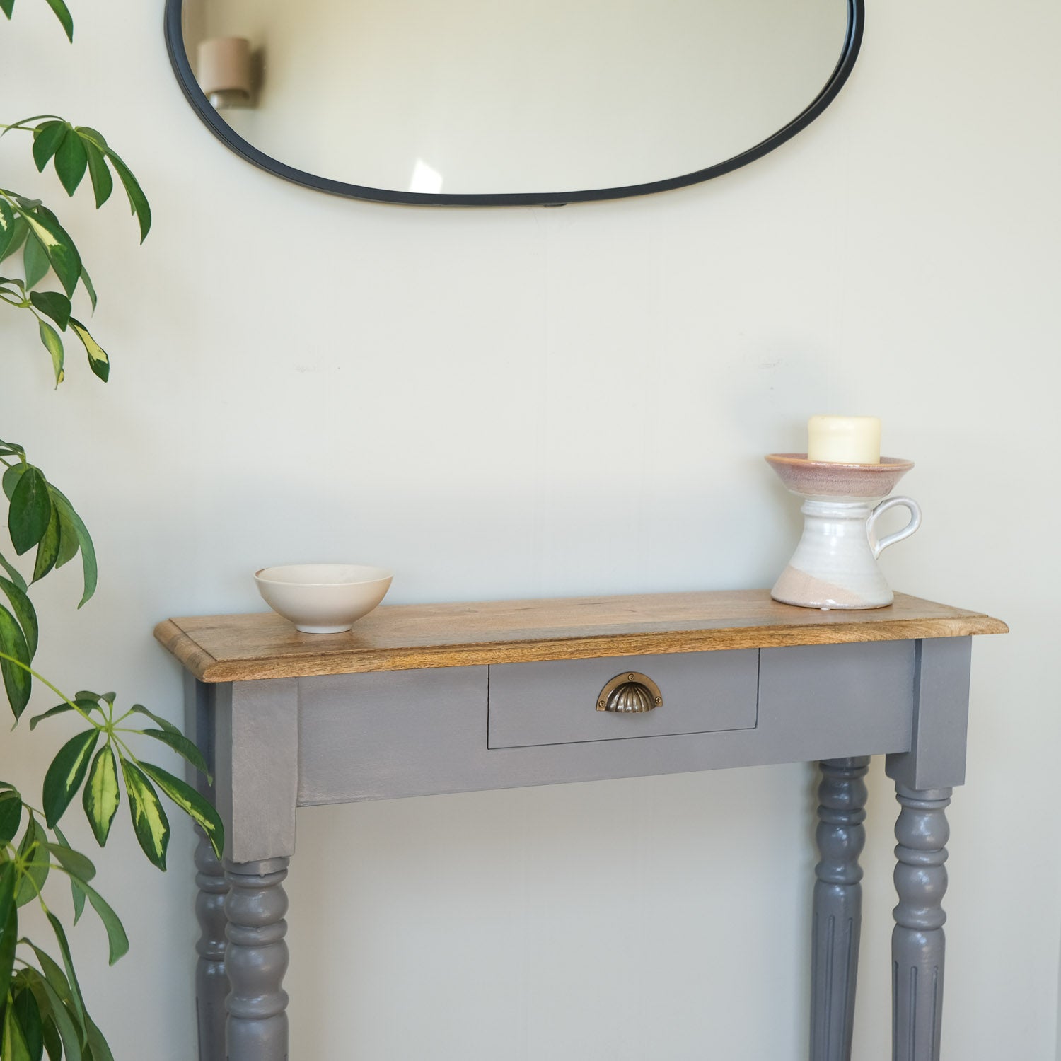 Console table with wooden top and gray base against a white wall with a mirror above.