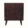 A small light walnut Marina cabinet with two carved doors featuring a pineapple pattern and brass knobs, perched on four short Nordic-style legs.