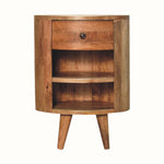 A curved bedside table, with 1 drawer and 2 open shelves, handmade from solid mango wood, in a natural finish.