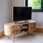 A neutral living room, featuring a large rounded TV stand made from a natural brown wood. 