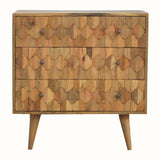 A medium-sized chest of drawers with a natural finish, featuring a hand-carved pineapple pattern on the front and brass knobs. It is on four short Nordic-style legs.