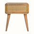 A curved wooden bedside table with a woven drawer front.