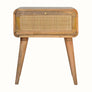 A curved wooden bedside table with a woven drawer front.