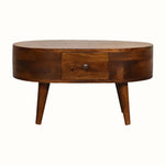 A small round chestnut-colored coffee table made of mango wood, with four tapered legs and two drawers with brass knob hardware.