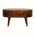 A small round chestnut-colored coffee table made of mango wood, with four tapered legs and two drawers with brass knob hardware.