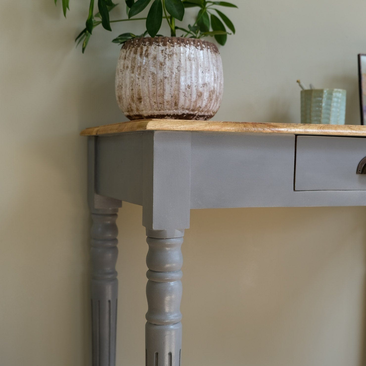 Wooden table with a plant and a small container on a neutral background