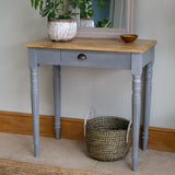 Gray console table with wooden top against a wall, featuring a basket on the floor.