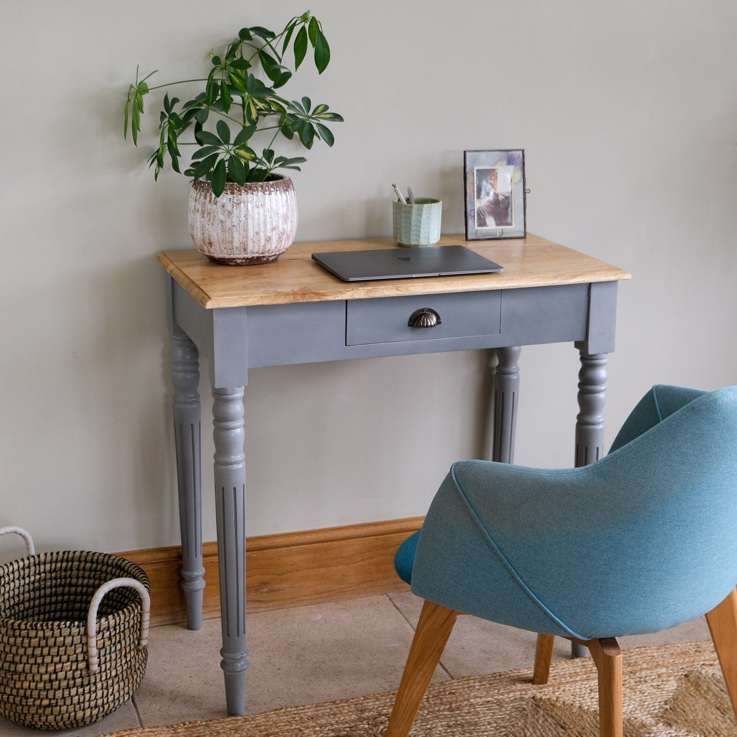 Small desk with a plant, laptop, and photo frame in a home office setting.